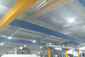 Industrial ceiling with yellow crane and blue fabric ductwork for ventilation.